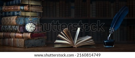 Old clock on background of old books an open book and a fountain pen in an inkwell. Ð¡lock as a symbol of time books are symbol of knowledge. Concept on the theme of history, nostalgia, culture.  Royalty-Free Stock Photo #2160814749