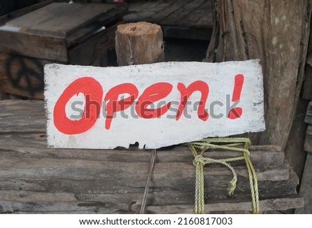 A white wooden vintage board sign with red letters written on the word Open