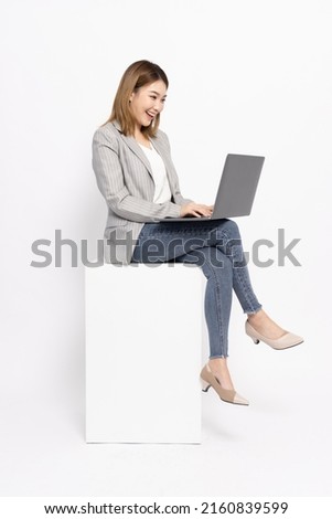 Attractive Asian businesswoman sitting and using laptop computer isolated on white background