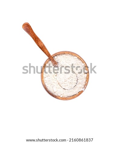 Top view of a wooden bowl with wheat flour and a spoon inside the flour. Copy space, white background.