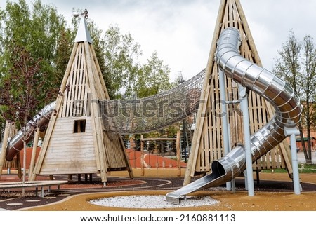 Large attraction of children's slides, climbing net, pyramids of logs, playground for kids, slide trumpet, summer vacation in the park, family recreation, outdoor entertainment. High quality photo
