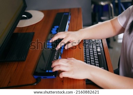 Person with blindness hands using computer with braille display or braille terminal a technology assistive device for persons with visual impairment. Royalty-Free Stock Photo #2160882621