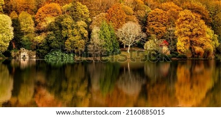 Panorama of the reflection of the autumn foliage of the forest in the water. Autumn forest river reflection. Autumn forest reflected in river water. Autumn river reflection Royalty-Free Stock Photo #2160885015