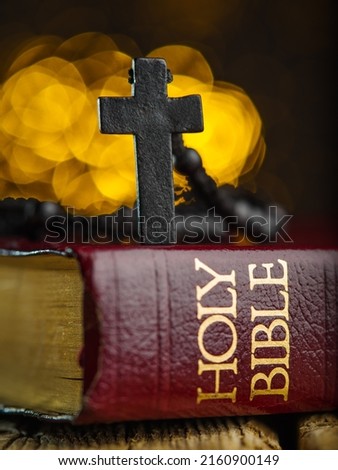 Macro shot. Crucifixion on the Holy Bible on a yellow fantasy background. Symbols of spirituality, religion, catholicism. There are no people in the photo. Advertising, banner, invitation.