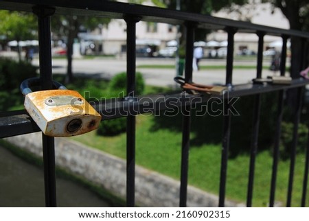 Love padlock - Padlock attached to a railing of a bridge to symbolize love, friendship and respect - aged by time