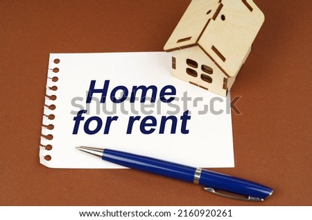 Business concept. On a brown surface is a house, a pen and a notepad with the inscription - Home For Rent