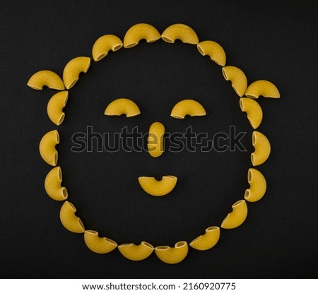 Macaroni smiley. Pasta picture. Pasta on a black table. raw pasta