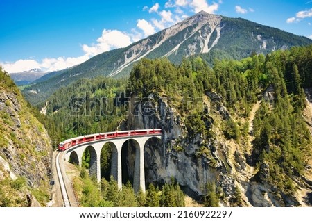 Landwasser viaduct in the Davos mountains near Filisur. Beautiful old stone bridge with a moving train. Spring Time. Royalty-Free Stock Photo #2160922297