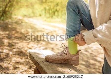Child tying up laces his sneakers in spring park for walk. Girl ties bow on her shoe outdoors. Health and sport concept. High quality photo
