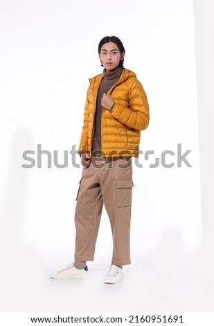 fashion model. full body young man in warm jacket with khaki pants posing in studio