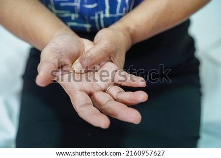 Asian senior woman pain her hand and finger, De Quervain's tenosynovitis.