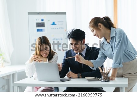 Cheerful asian people colleagues working together sit at desk look at computer screen discuss new project search solutions joking to increase effective communication concept, chart on whiteboard. Royalty-Free Stock Photo #2160959775