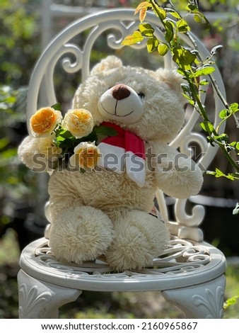 Cute teddy bear holding yellow roses