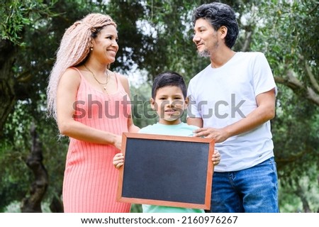 Beautiful happy family holding a blackboard with free space for text