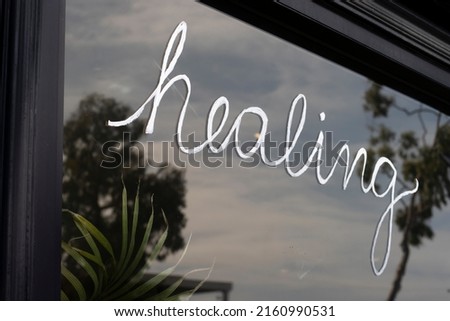 Closeup of the handwritten word "healing" on a storefront window.