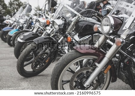Motorcycles parked in a line in a motorcycle parking lot. Close-up of the front wheel of a motorcycle Royalty-Free Stock Photo #2160996575