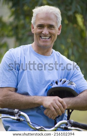 Mature man with helmet on bicycle, smiling, portrait