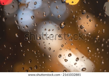 Raindrops on blue glass background. Street bokeh out of focus. abstract background