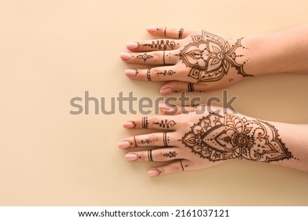 Female hands with beautiful henna tattoo on color background, closeup