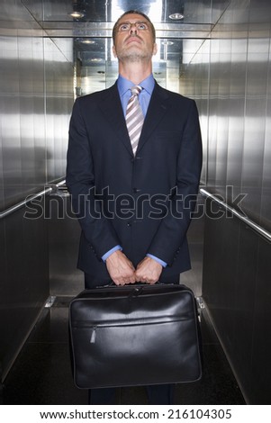 Businessman in elevator, looking up