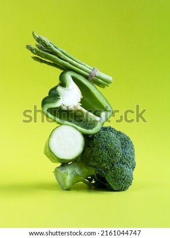 Fresh green vegetables balance on the table. Equilibrium floating food balance of broccoli, bell pepper, zucchini and asparagus on a green background Royalty-Free Stock Photo #2161044747