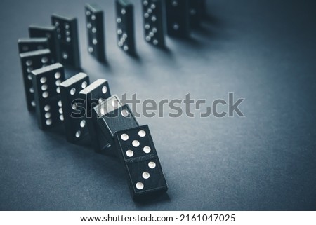 Black dominoes chain on a dark table background. Domino effect concept Royalty-Free Stock Photo #2161047025