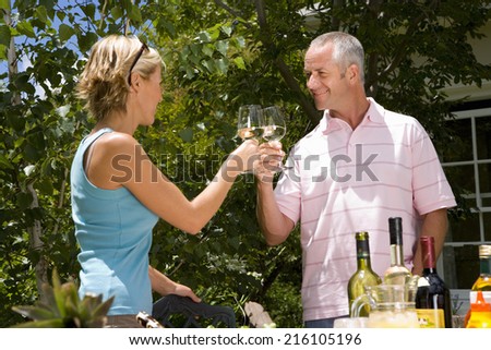 Couple proposing toast with wine glasses in garden, low angle view