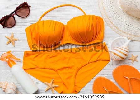 Woman swimwear and beach accessories flat lay top view on colored background Summer travel concept. bikini swimsuit, straw hat and seasheels. Copy space Top view.