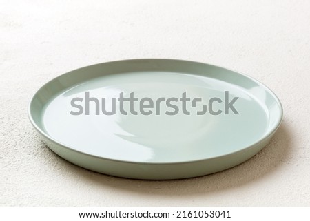 Perspective view of empty blue plate on cement background. Empty space for your design.