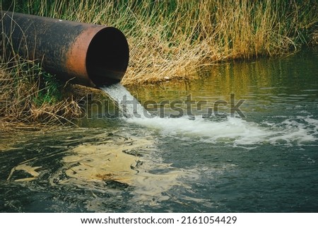 Draining sewage from pipe into river, pollution rivers and ecology Royalty-Free Stock Photo #2161054429