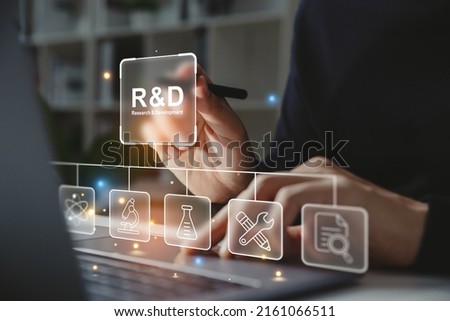 Hand of businessman holding a pen pointing to R and D icon for Research and Development on laptop screen. Manage costs more efficiently. R and D innovation concept. Royalty-Free Stock Photo #2161066511