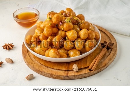 homemade Loukoumades are sweet dough balls dipped in sweet syrup and sprinkled with nuts.