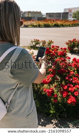 Young woman taking pictures of flowers on the street