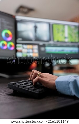 Close up shot of video graphic editor using specialized software to edit movie footage and improve visual quality. Professional videographer sitting at multi monitor workstation enhancing film frames. Royalty-Free Stock Photo #2161101149