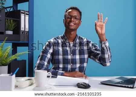 Happy positive smiling heartily young adult approving project idea while making cool symbol with hand. Cheerful joyful business man in office validating worker good job with great work hand gesture.