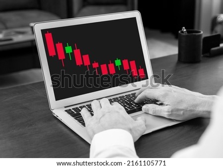 Man working with declining candlestick graph at laptop. Down movement in product price. Crisis, stock market analysis. Investment, finance concept. Trader hands at keyboard. High quality photo