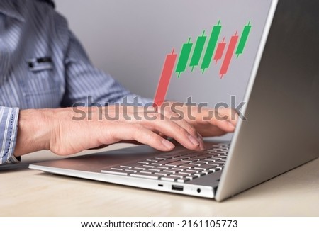 Man using candlestick graph for tracking price movement. Trader hands at laptop keyboard. Stock market analysis, investment, finance concept. High quality photo
