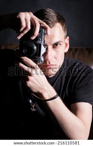 Young man with old camera in dark studio