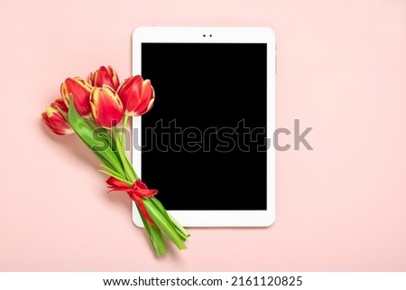 Bouquet of red tulip flowers and tablet with black digital screen on pink background Floral holiday card Top view Flat lay Happy Mother's, Valentine's, Women's Day, Flower shop concept Mock up