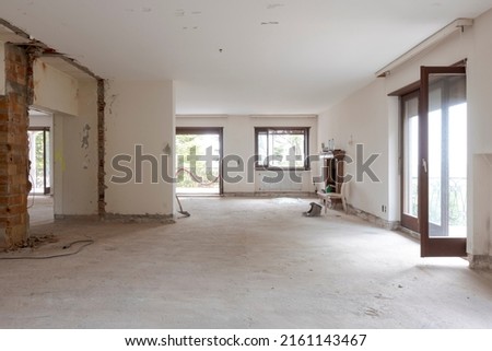 Large bright room with many windows of an old villa undergoing demolition and renovation. The walls have been knocked down and the floor is gone. Nobody inside Royalty-Free Stock Photo #2161143467