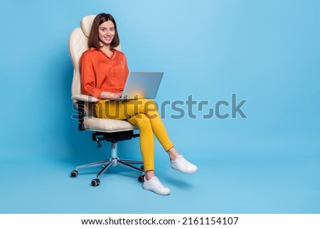 Portrait of attractive cheery girl sitting in armchair using laptop typing project isolated over bright blue color background Royalty-Free Stock Photo #2161154107