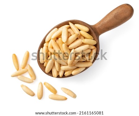 Roasted pine nuts in the wooden spoon, isolated on white background, top view. Royalty-Free Stock Photo #2161165081