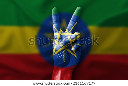 Hand making the V victory sign with flag of ethiopia