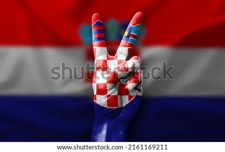 Hand making the V victory sign with flag of croatia