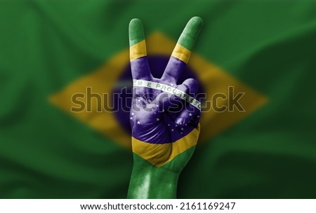 Hand making the V victory sign with flag of brazil