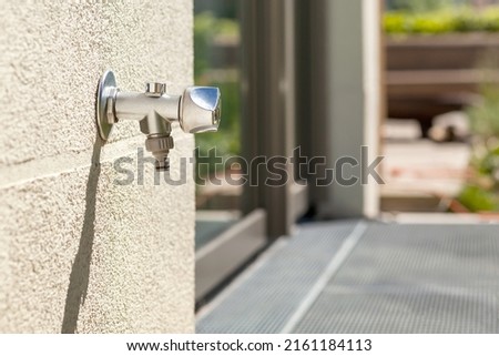 Tap Water on outside wall. Outdoor garden Faucet on yard background. 