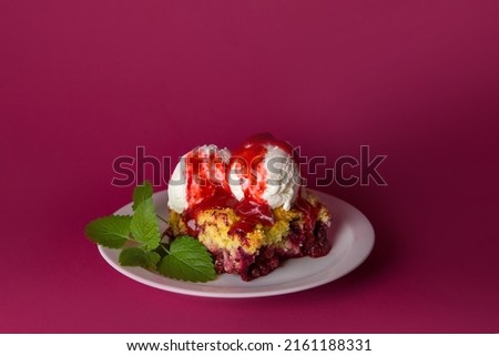 Delicious pie with grated cherries and blueberries with vanilla ice cream balls,poured with strawberry syrup on a red background.Horizontal selective focus.summer desserts.for menus and ads.copy space