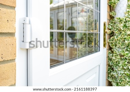 Shallow focus of door hinges seen on a newly installed double glazed PVC door which leads to a kitchen. Seen with installed leaded windows. Royalty-Free Stock Photo #2161188397