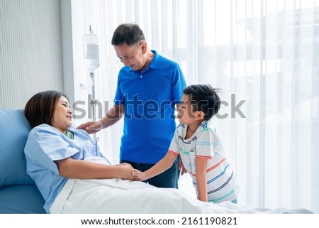 Asian woman, sick, stay in hospital. lying on the patient's bed beside the window A son and family came to visit and encourage Royalty-Free Stock Photo #2161190821