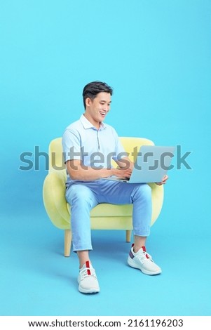 Asian handsome and cheerful young man working on laptop and sitting on sofa, isolated on background Royalty-Free Stock Photo #2161196203
